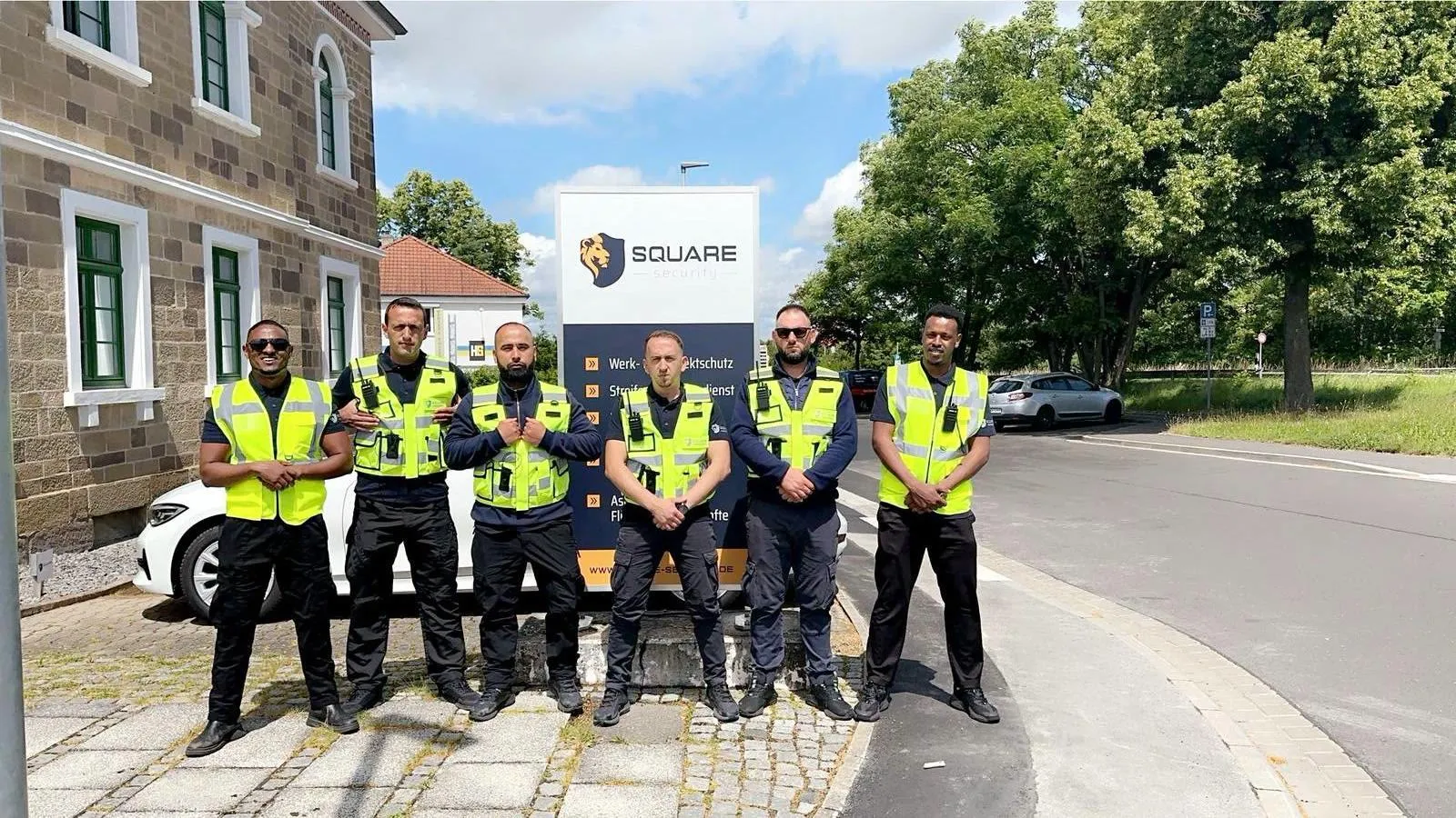 Das Team von Square Security in Warnwesten vor dem Firmenaufsteller